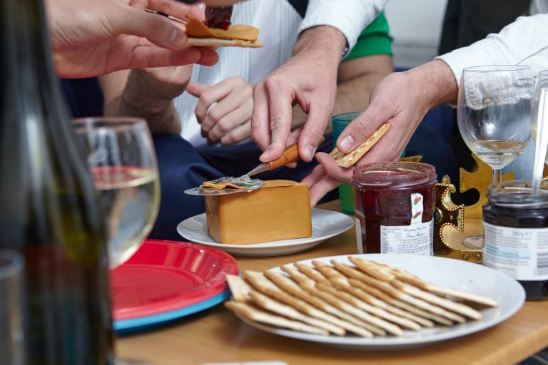 People around a table cutting a slice of brunost